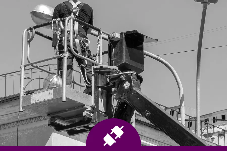 electrician fixing wiring in a street light in a parking lot