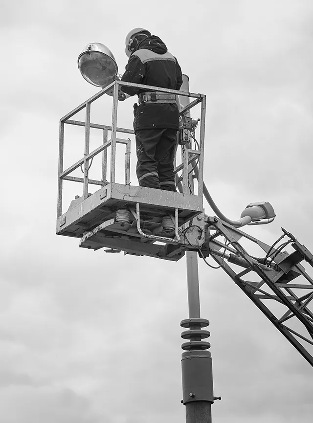 Electrician performing maintainance on a parking lot street light